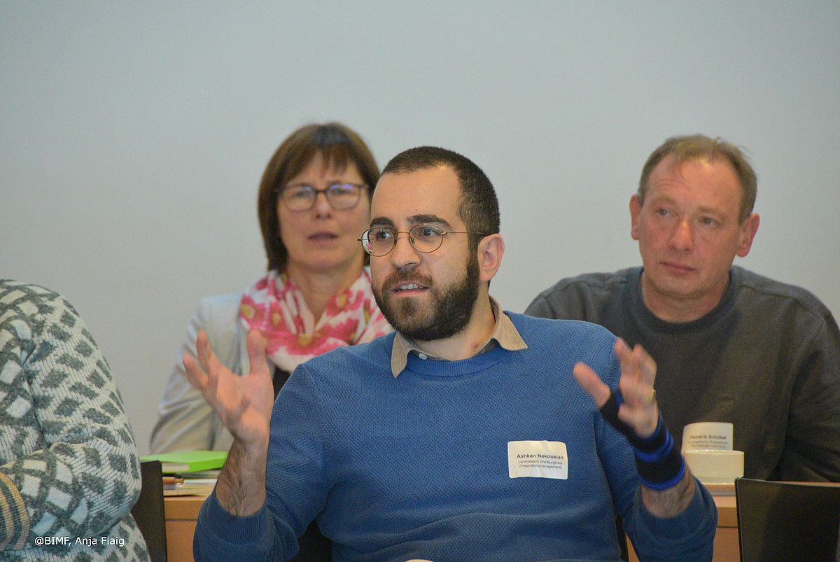 Ehrenamtsveranstaltung 20.11.2024 Publikum, 3 Personen sitzend im Vordergrund ein Mann mit blauem Pullover, im Hintergrund eine Frau mit Halstuch und ein Mann mit dunklem Pullover