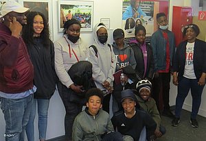 Menschen stehend und kniend vor einer Wand