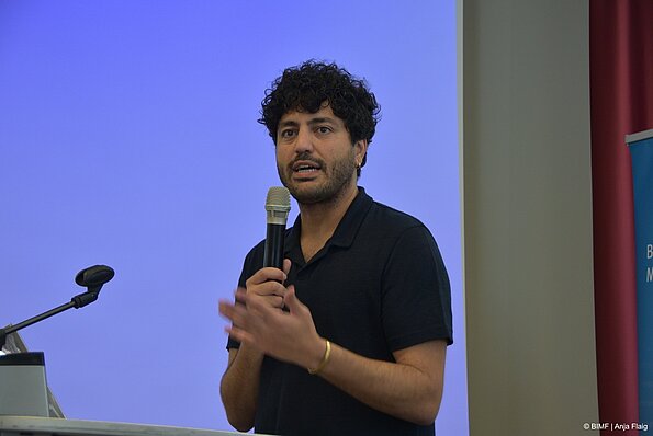 Foto MO VA: Referent stehend mit einem Mikrofon in der Hand