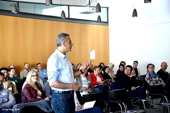 MO VA 17.05.2025 Publikum, viele Personen sitzend in Reihen, eine männliche Person stehend