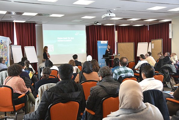 MO VA 20.04.2024 Publikum sitzend von hinten, am Pult ein Mann spricht in ein Mikrofon