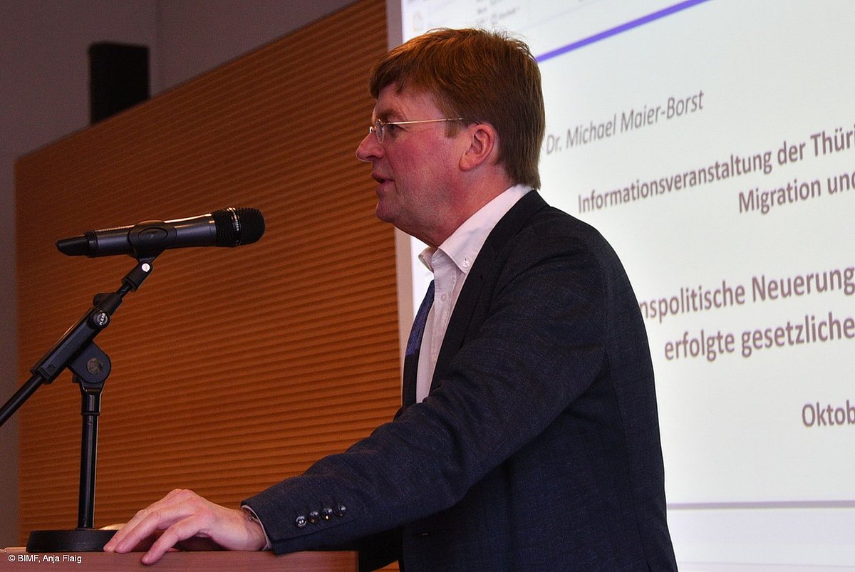 Herr Dr. Michael Maier-Borst, stehend am Mikrofon, im Hintergrund die Präsentation