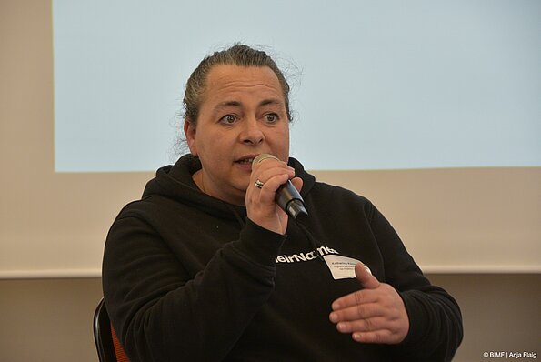 Foto MO VA: eine Frau sitzend und sprechend in ein Mikrofon in der Hand