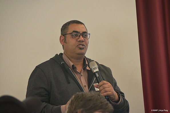 Foto MO VA: ein Mann mit Brille stehend mit einem Mikrofon in der Hand