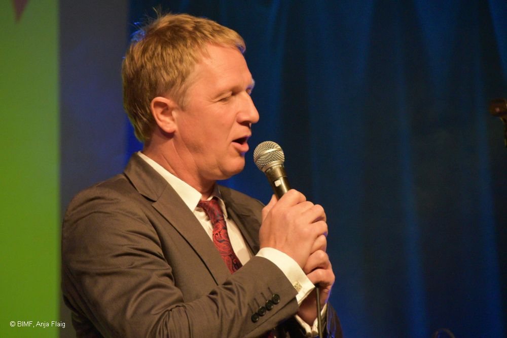 Musiker am Mikrofon stehend, beide Hände am Mikrofon