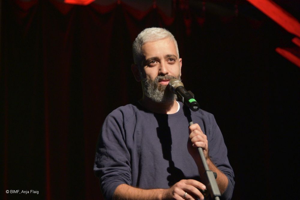 Mann mit Bart stehend vor einem Mikrofon