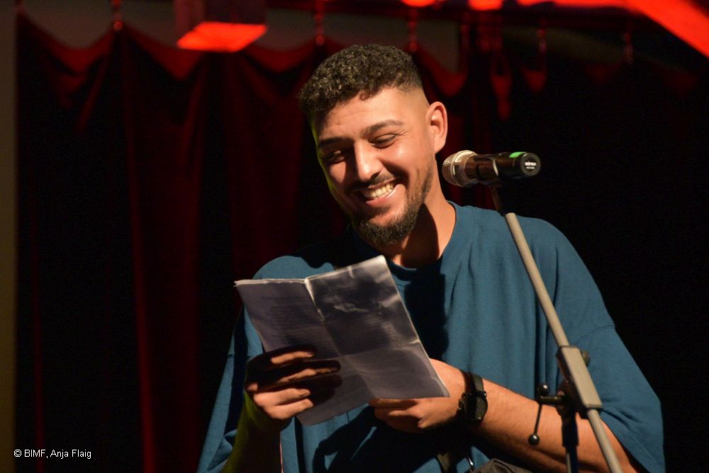 Mann mit Zettel in der Hand stehend vor einem Mikrofon