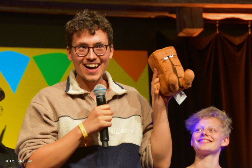 Der Gewinner unseres Poetry Slams Benjamin Poliak mit seinem Gewinn: der Plüschfigur Bernd das Brot